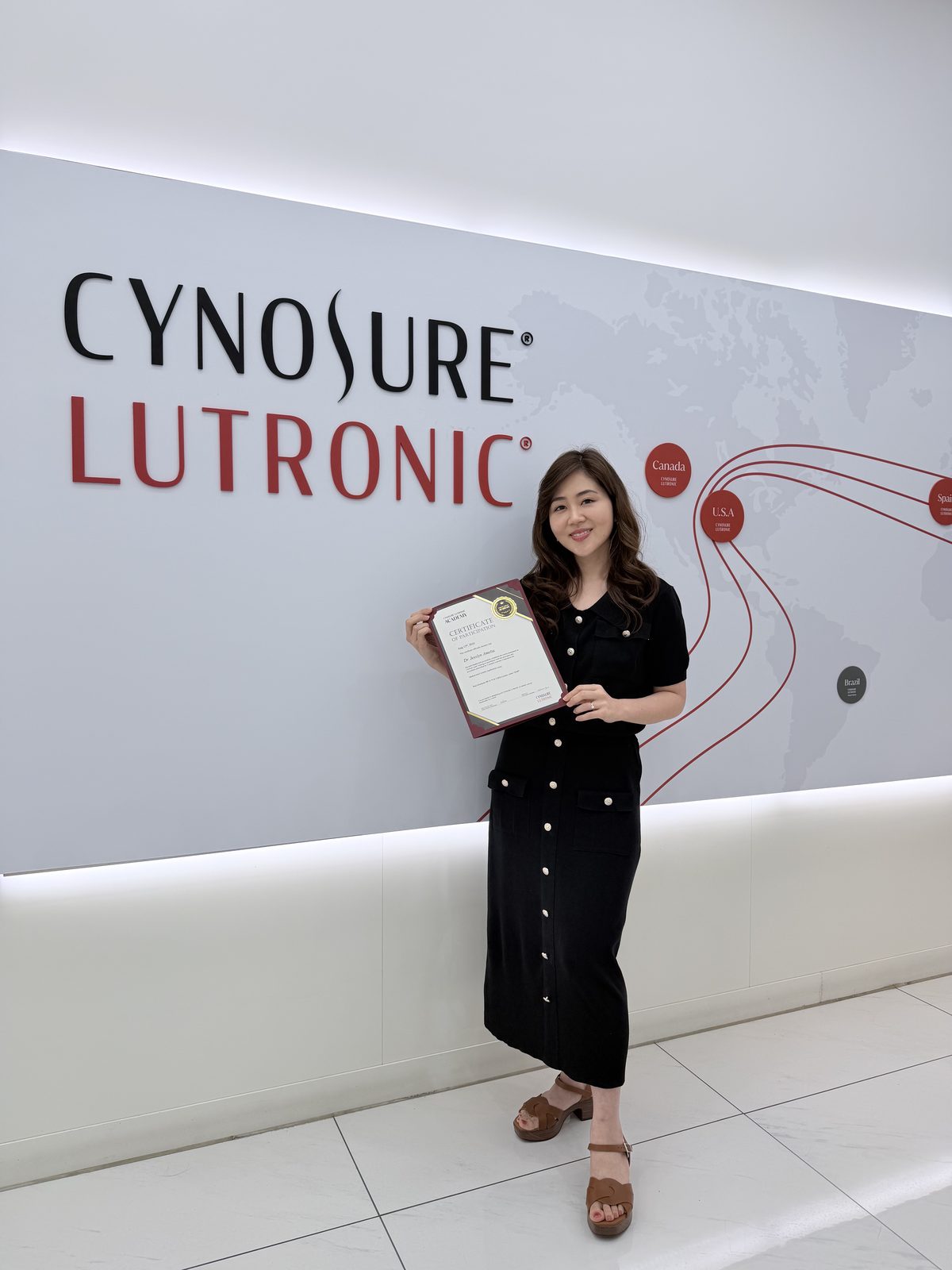 dr. Jesslyn Amelia holding the Cynosure Lutronic Academy Certificate of Participation for XERF clinical laser training